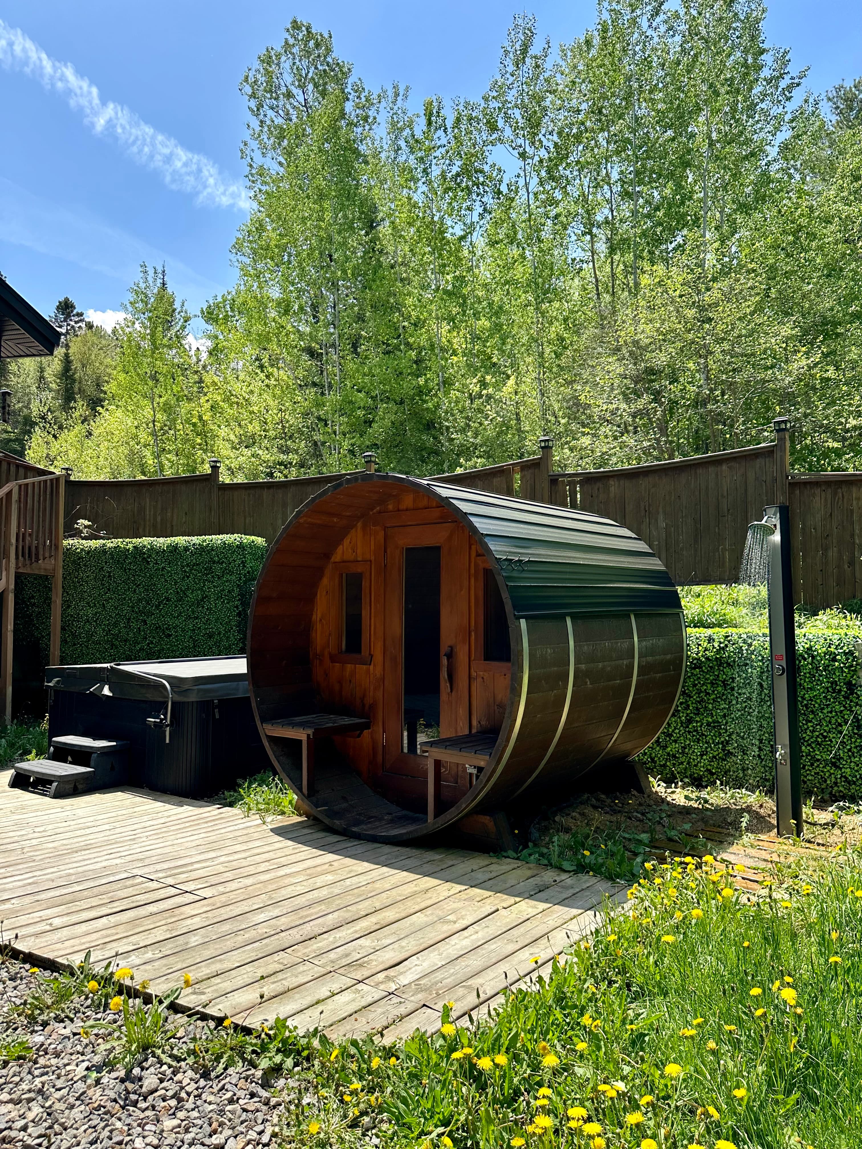 Barrel sauna in summer with outdoor shower